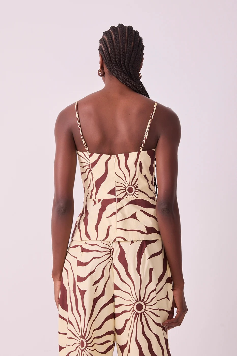 Back view of a model wearing a sleeveless matching set top and pants in brown alvorecer pattern