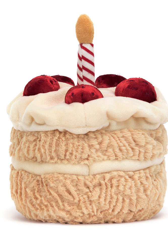 Plush birthday cake toy with cream frosting, red berries, striped candle on top