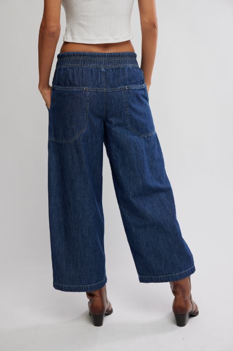 Back view: dark blue wide-leg pull-on jeans with elastic waistband and patch pockets
