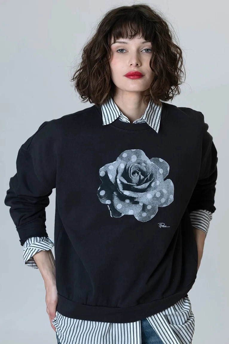 Cozy sweatshirt in dark black with gray rose graphic and striped shirt collar peeking.