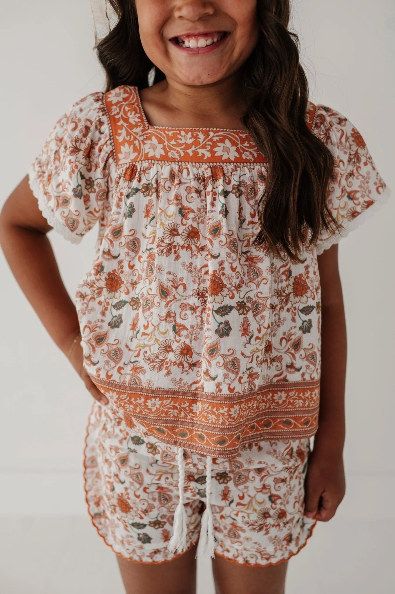 Close-up: square-neck peasant top with orange floral border and gathered bodice