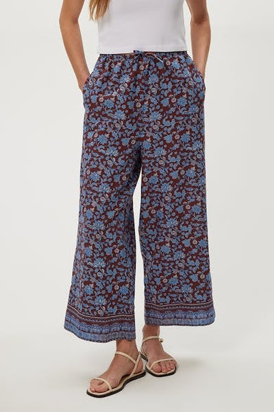 Blue drawstring pants with red floral print, relaxed wide-leg fit.