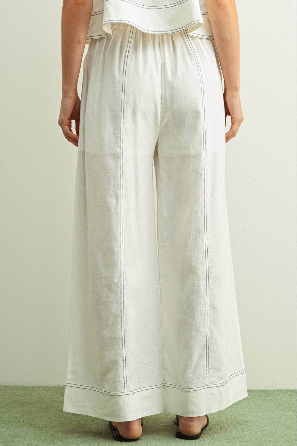 back view of woman wearing white stitched wide leg linen pants