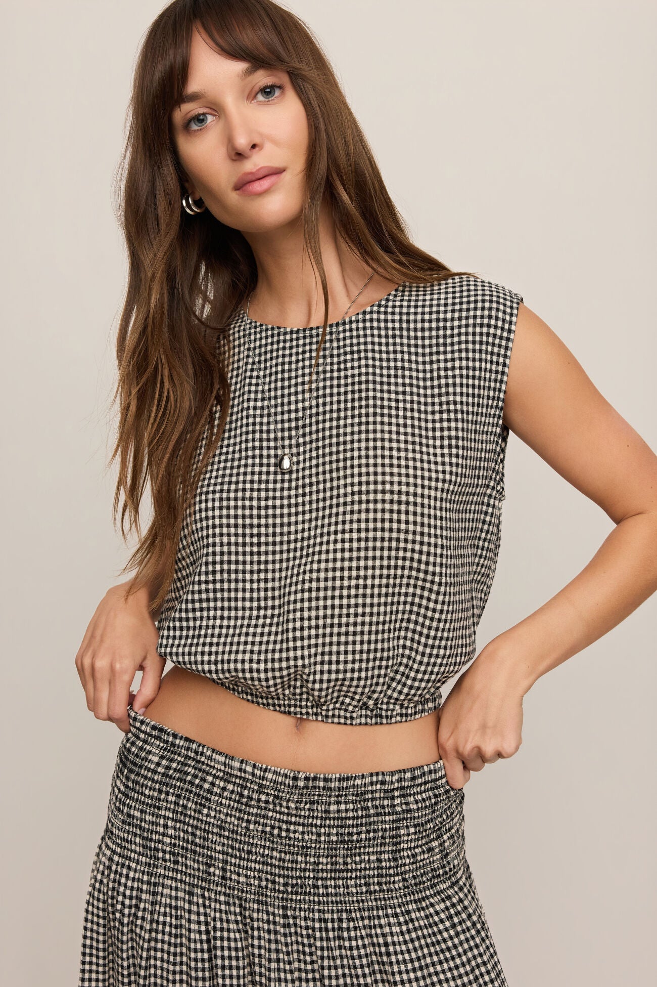 Front view of woman wearing Merit Gingham top in black & white with matching skirt