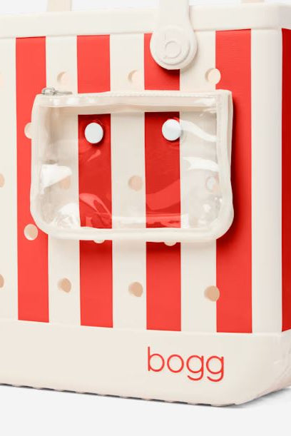 A Bogg brand cooler bag with red and white vertical stripes, featuring a clear zippered front pouch and a white base with the red 'bogg' logo.