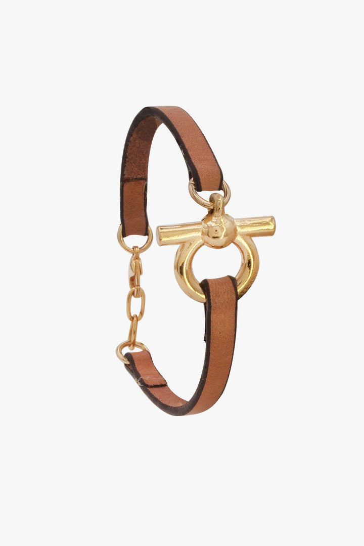 A slim brown leather bracelet with a gold-tone toggle clasp and chain link detail, shown on a plain light gray background.