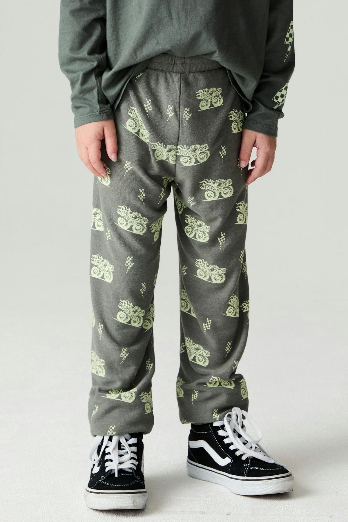A child wearing safari green monster truck jogger style pants with a matching long sleeve shirt