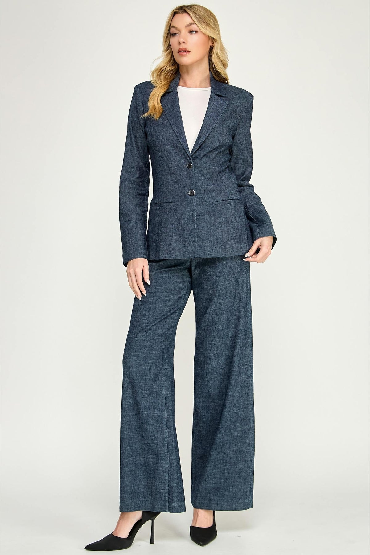 A woman modeling a matching lennox blazer in stargazer color and wide-leg trousers set, styled with a white top and black heels against a light gray studio background.