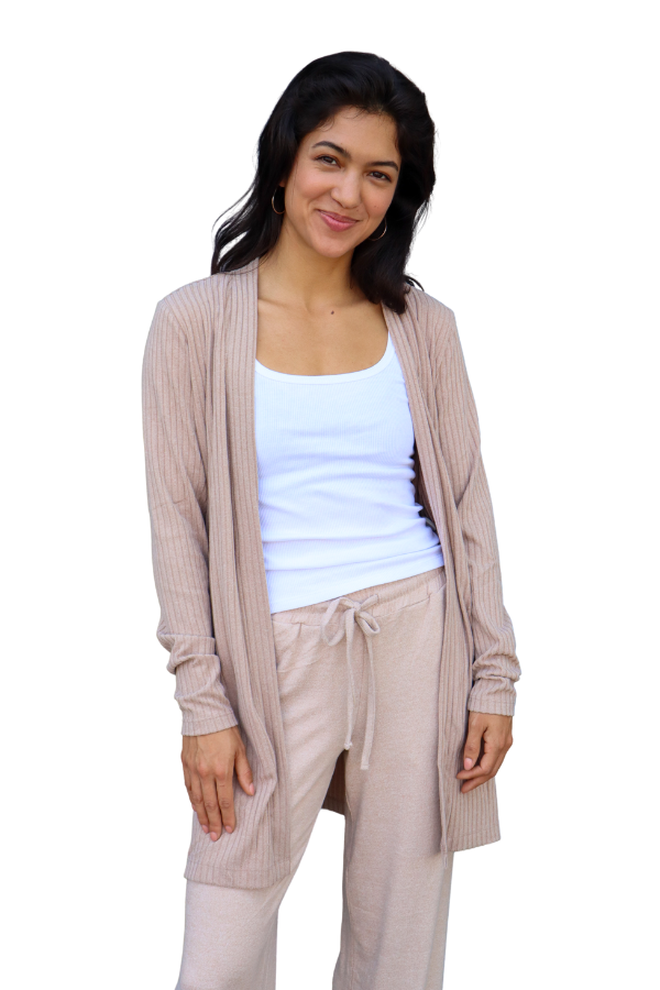 Woman wearing a beige cardigan over a white top and beige pants on a white background