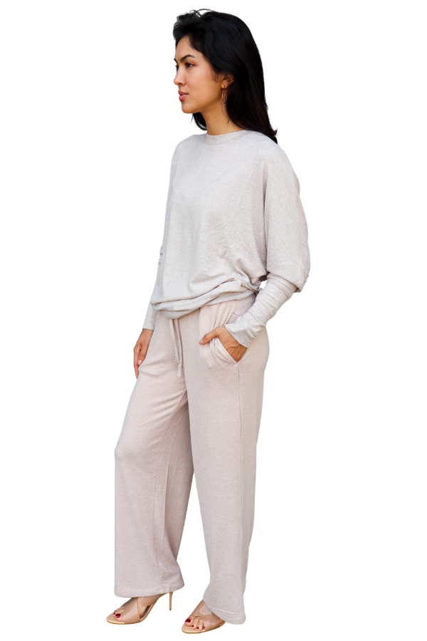 Woman wearing a light pink long-sleeve top and beige wide-leg pants on a white background