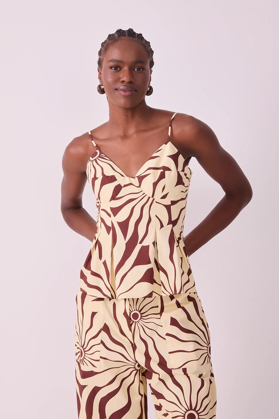A model wearing a sleeveless matching set top and pants in brown alvorecer pattern 