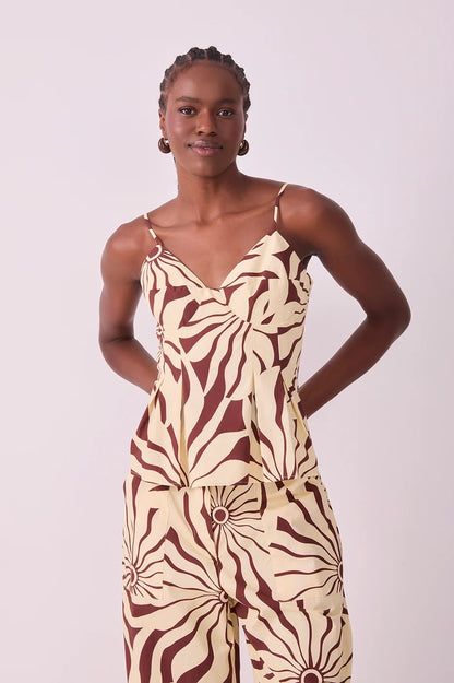 A model wearing a sleeveless matching set top and pants in brown alvorecer pattern 