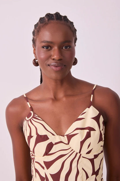 A woman with braided hair wearing a beige and dark brown abstract alvorecer patterned camisole top, photographed against a plain light background.