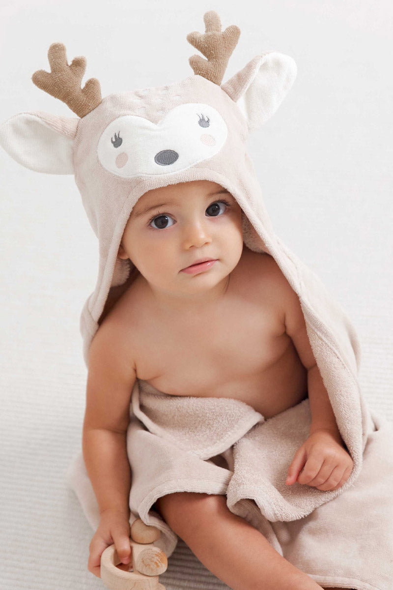 Baby wearing a hooded towel with fawn deer design on a white background