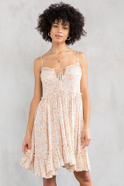 Woman wearing a natural peach floral dress against a plain background