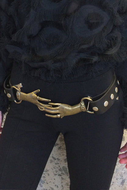 Person wearing a black outfit with a unique belt featuring a hand design.
