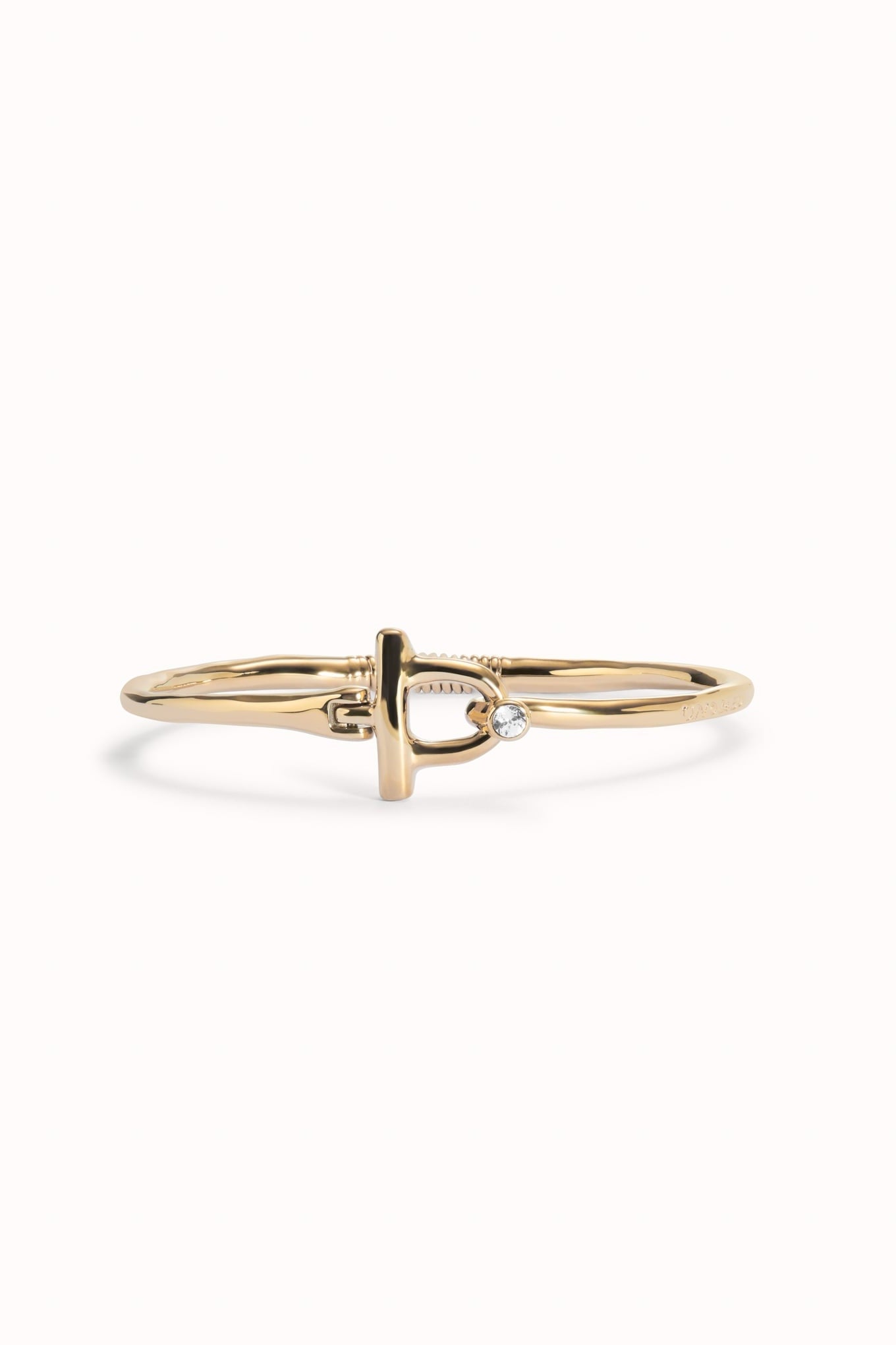 Indomable gold-tone bangle bracelet with heart-knot center and small clear stone