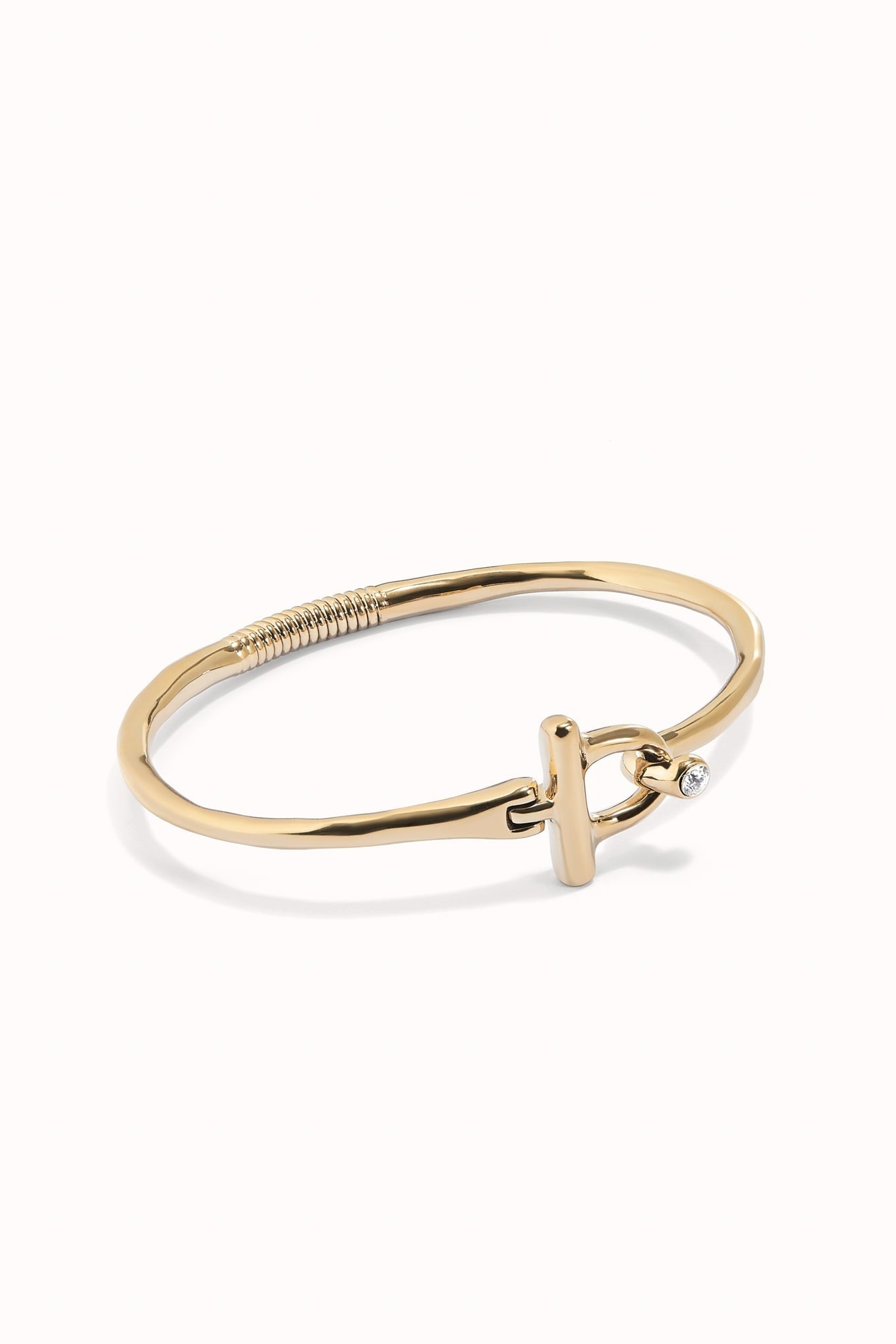Indomable gold-tone bangle bracelet with braided detail and knot charm with clear stone