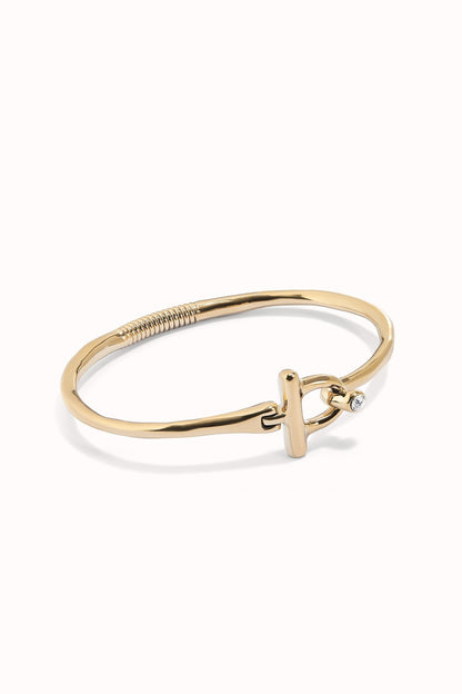 Indomable gold-tone bangle bracelet with braided detail and knot charm with clear stone
