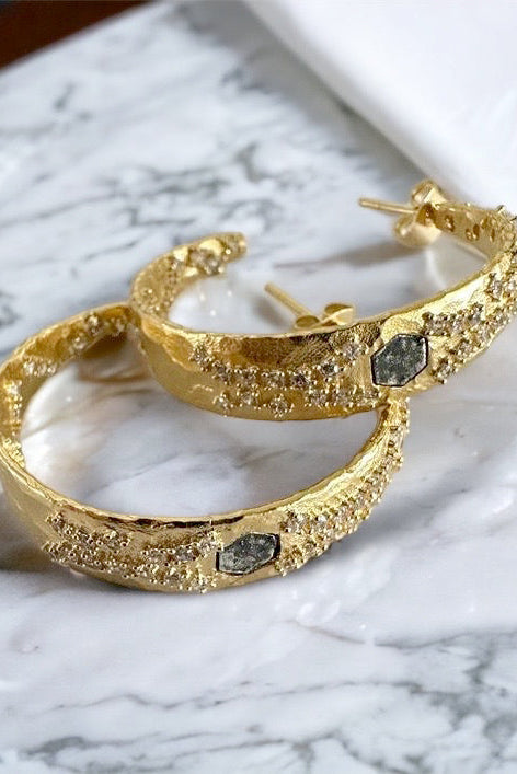 Gold hoop earrings with glitter texture and dark square stones