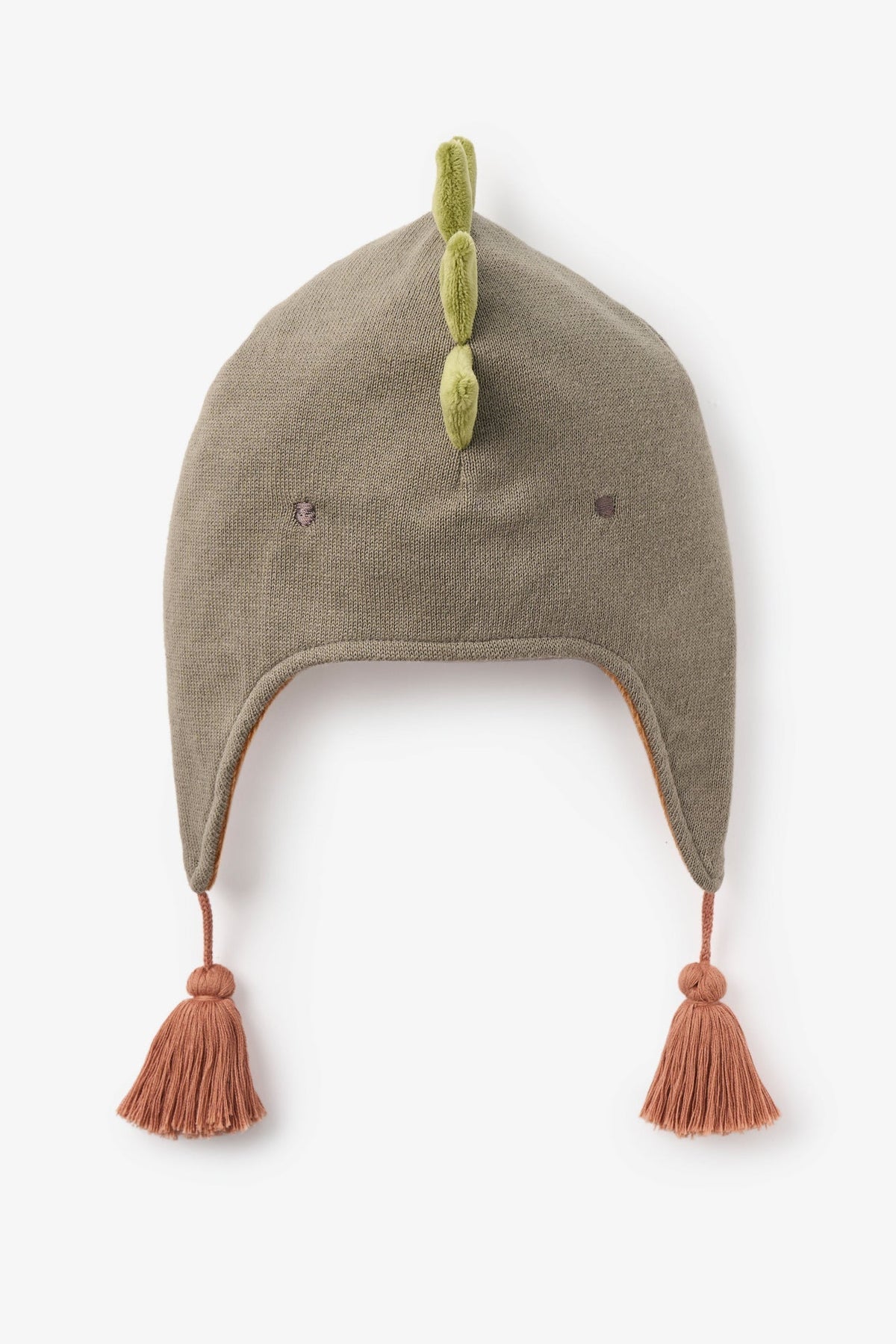A dinosaur-themed knit winter hat in a muted taupe-brown color, featuring three green felt spikes on top, small embroidered eyes, ear flaps with dusty rose tassel ties, and a small dusty rose bow on the front.