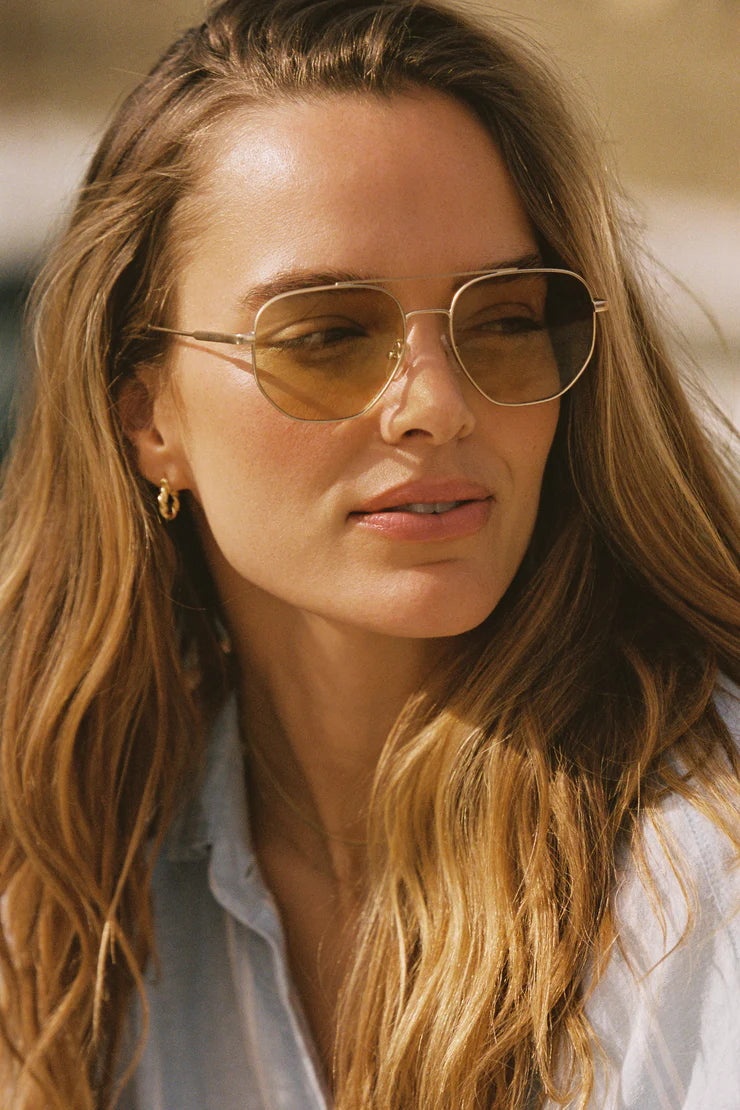 Aviator sunglasses on face, amber gradient lenses and thin gold frame