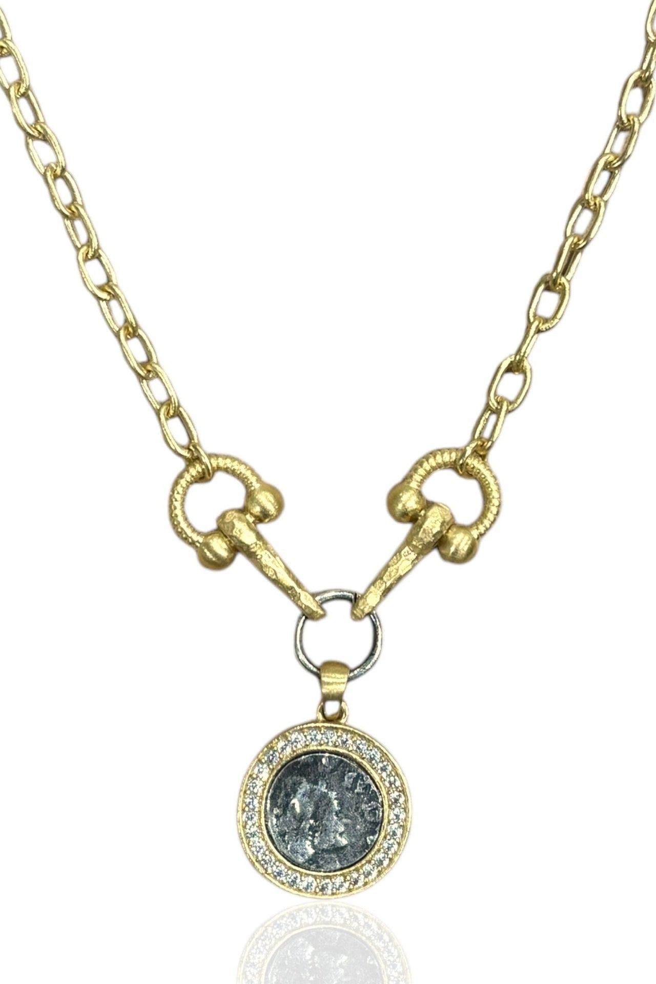 Gold necklace with a pendant featuring a dark stone and small diamonds on a white background