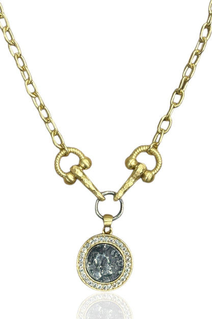 Gold necklace with a pendant featuring a dark stone and small diamonds on a white background
