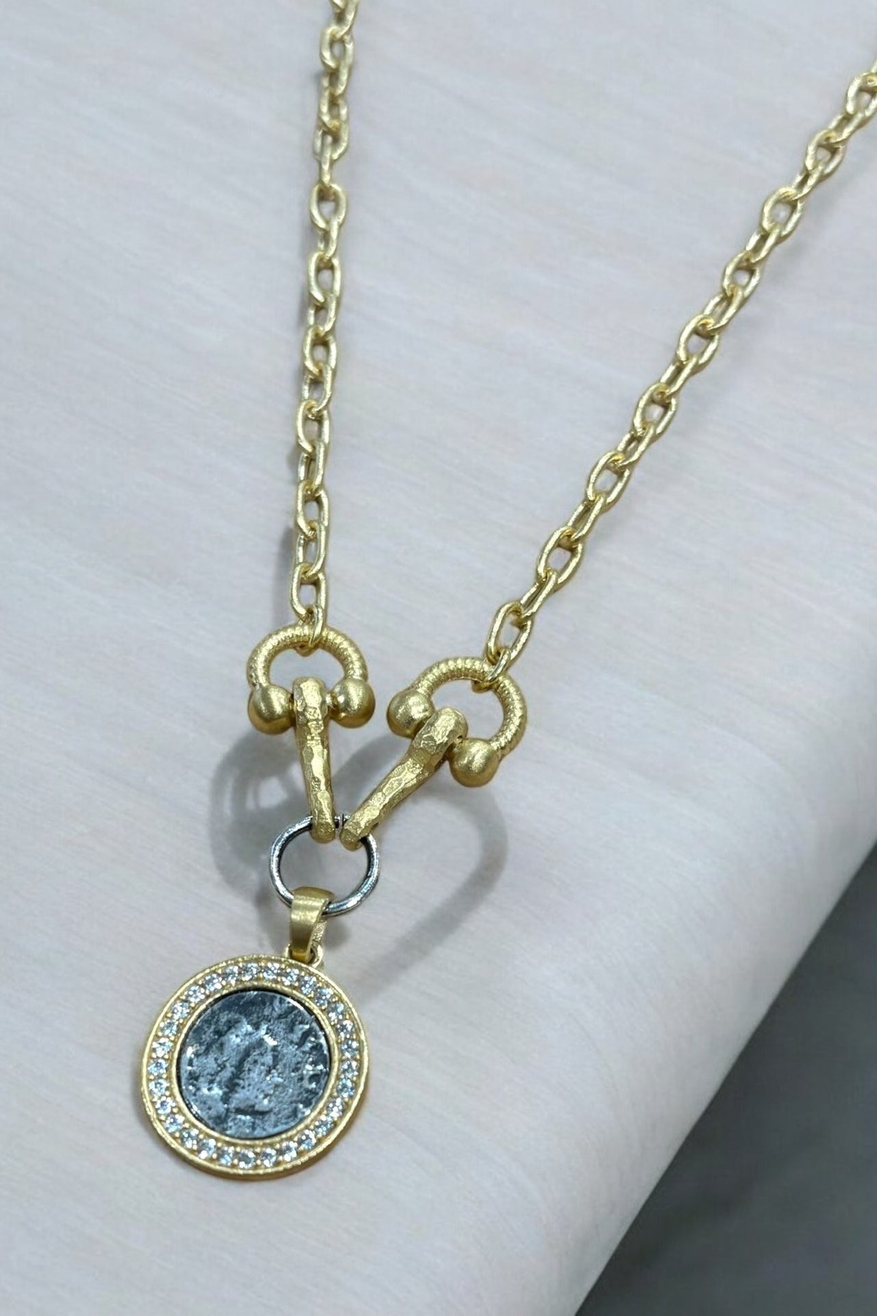 Gold necklace with a pendant on a white surface