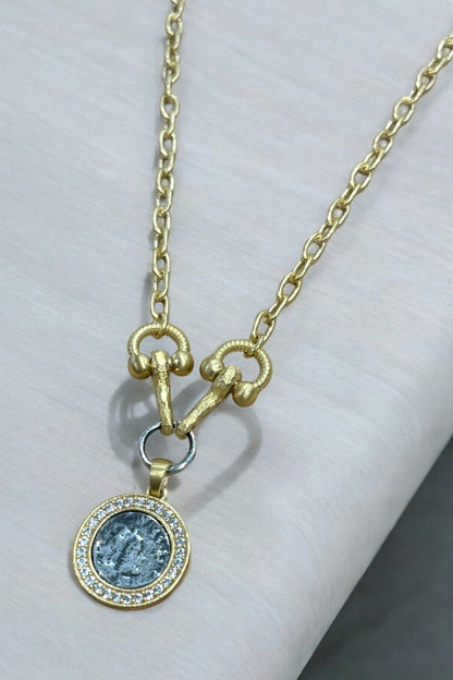 Gold necklace with a pendant on a white surface