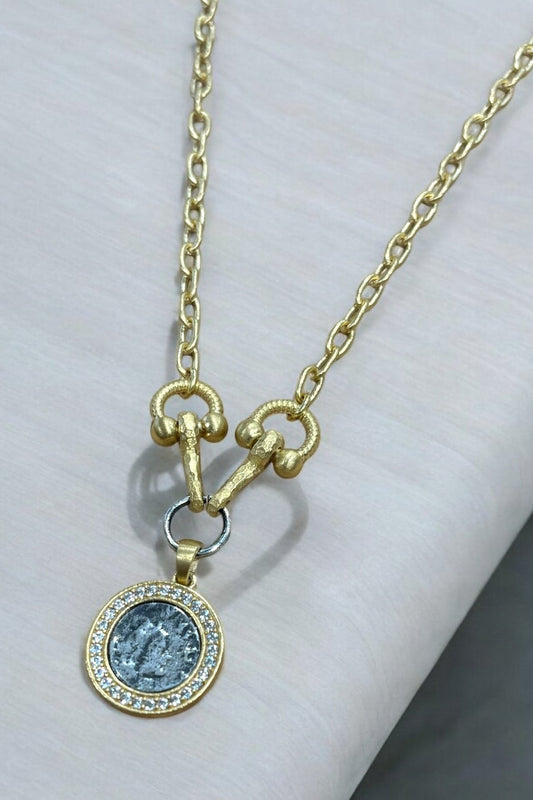Gold necklace with a pendant on a white surface