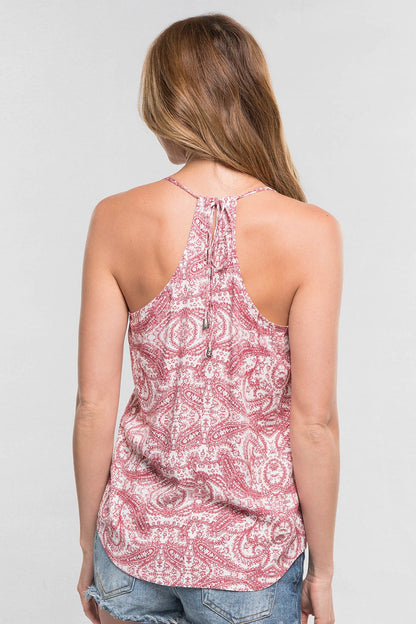 A woman viewed from the back wearing a burnt sienna combo paisley print halter tank top and denim shorts against a light gray studio background.