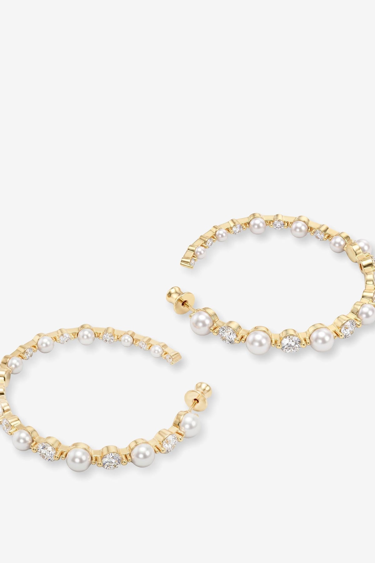 A pair of gold hoop earrings embellished with white pearls and small clear rhinestones, displayed on a light gray background.