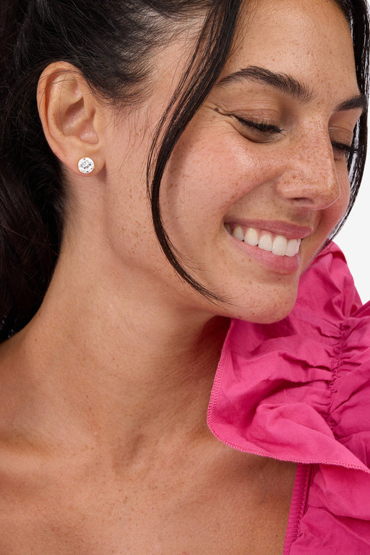 Gold-tone round stud earrings with clear cubic zirconia stone, side view