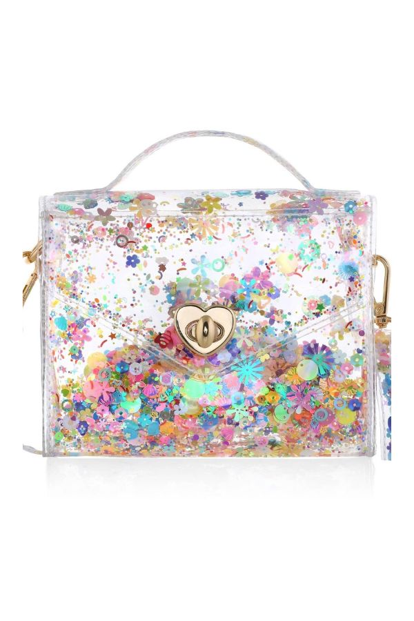 A clear plastic handbag filled with multicolored flower-shaped glitter, featuring a gold heart-shaped clasp, a top handle, and a matching wristlet strap on a white background.