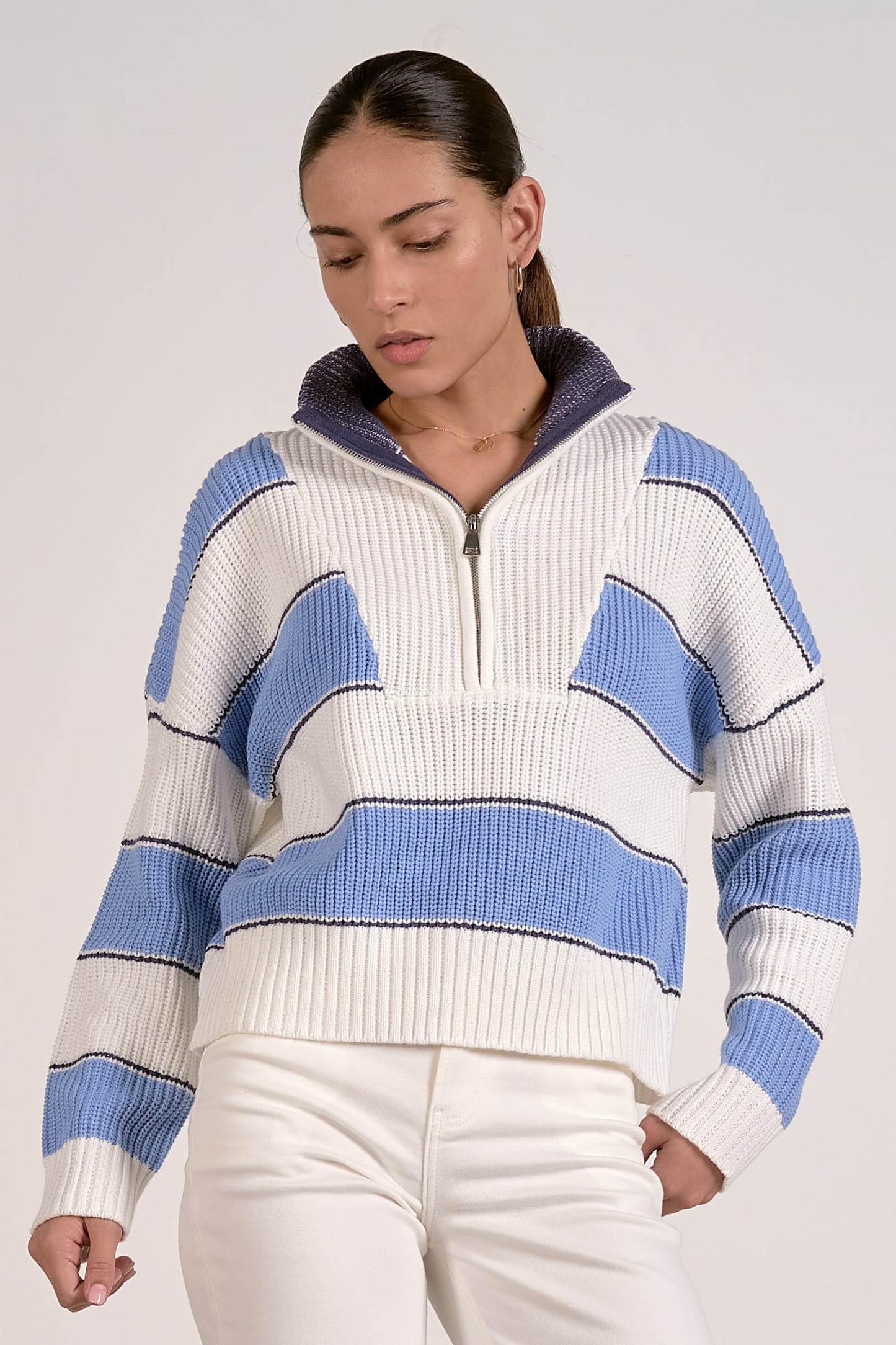 Woman wearing a blue and white striped quarter zipped sweater against a plain background