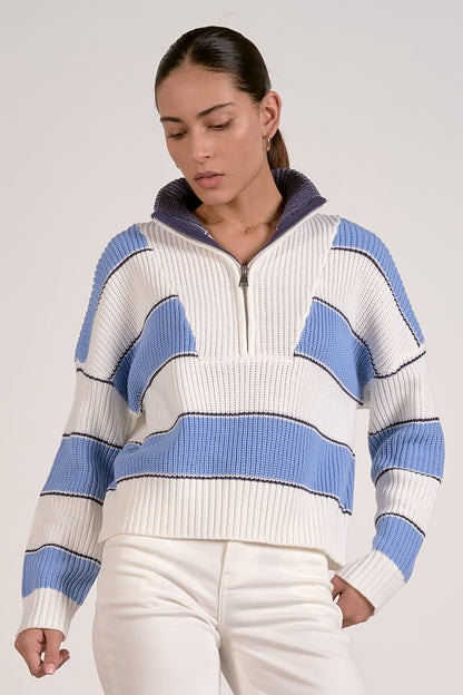 Woman wearing a blue and white striped quarter zipped sweater against a plain background