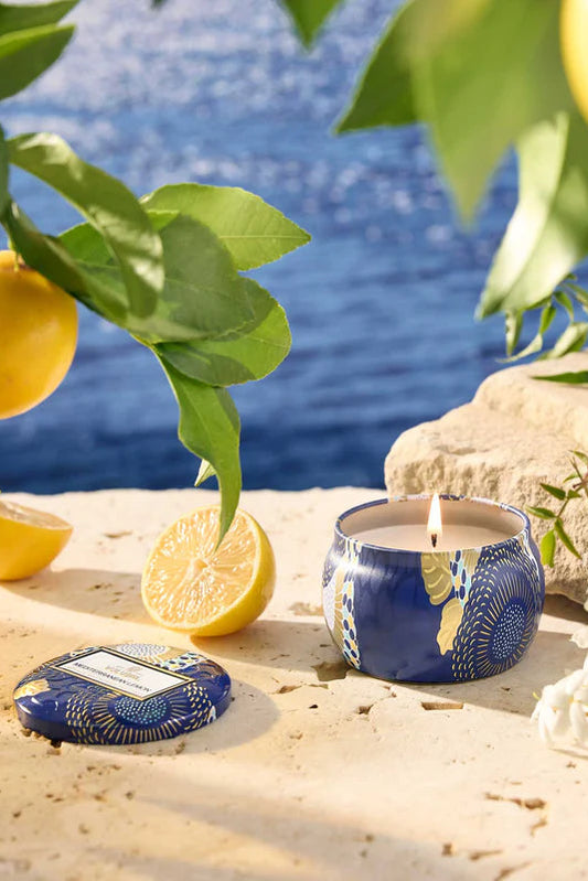 Mini tin candle in blue patterned tin with lit wick and matching lid