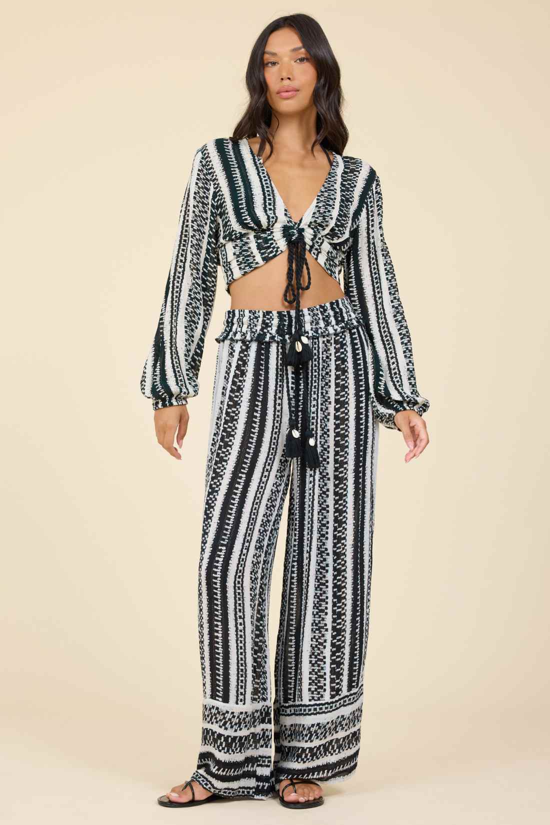 Woman wearing a black and white geometric patterned outfit on a beige background