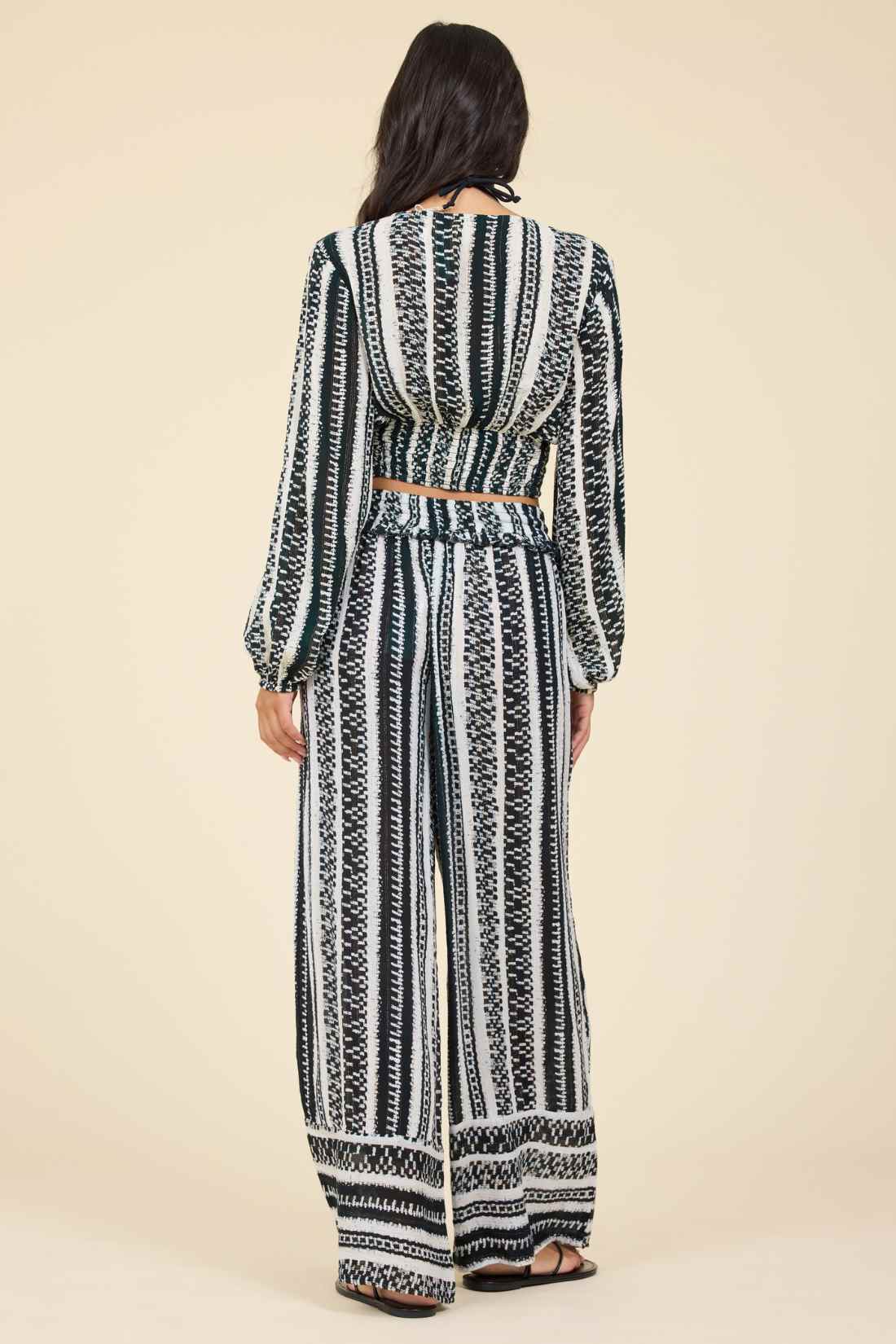 Back view of woman wearing a black and white geometric patterned outfit on a beige background