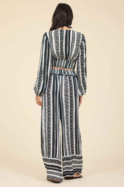 Back view of woman wearing a black and white geometric patterned outfit on a beige background