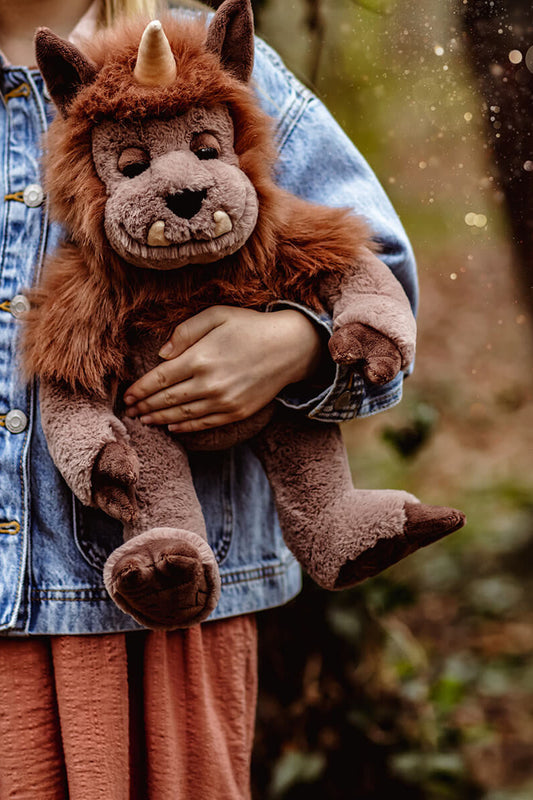 Person holding a plush toy with a quarry fantasy design in a natural setting