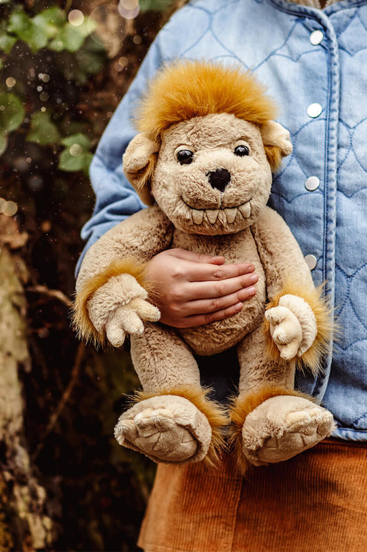 Person holding a plush bedrock toy outdoors with a natural background