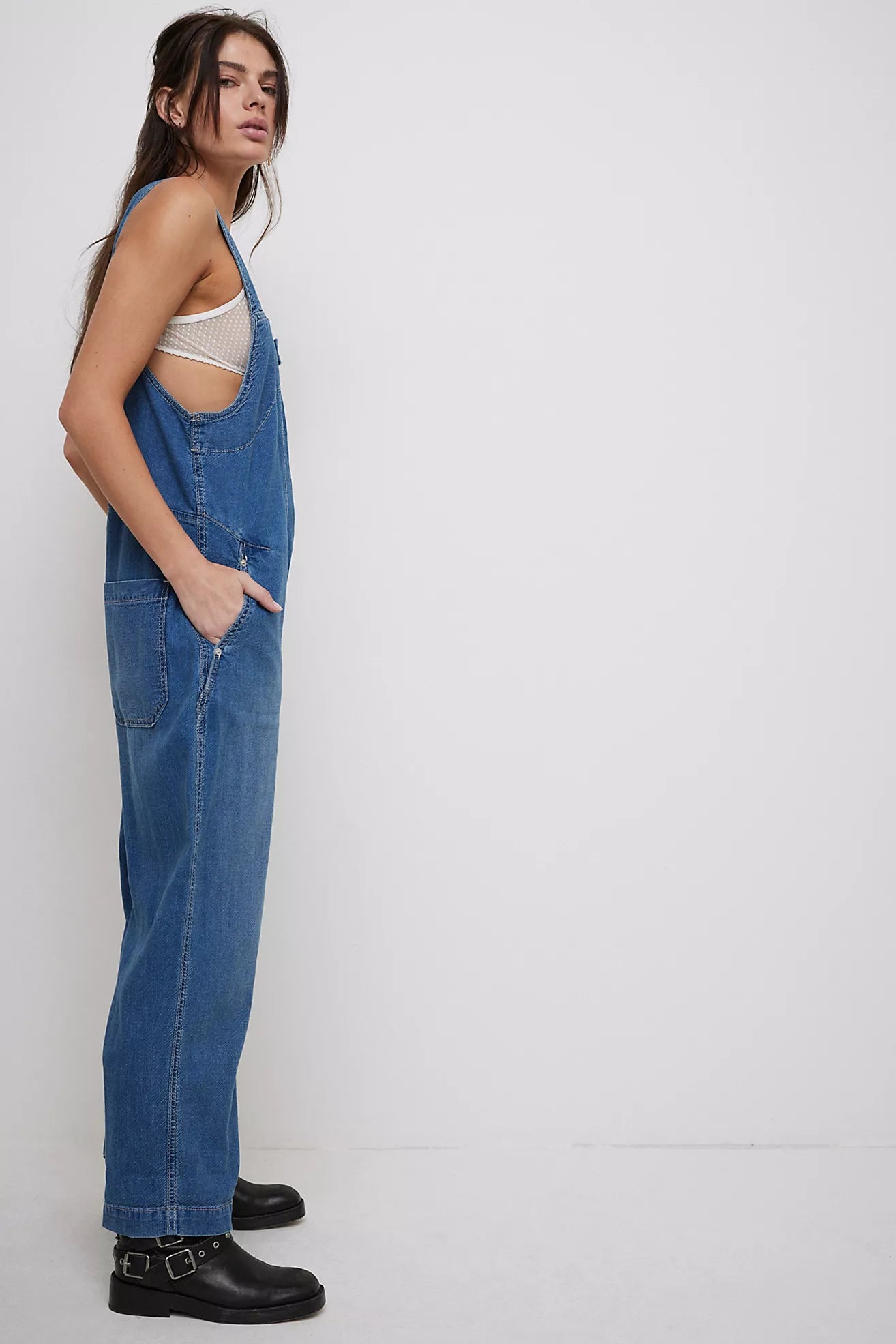 Mid indigo denim jumpsuit with wide legs and adjustable shoulder straps, side view