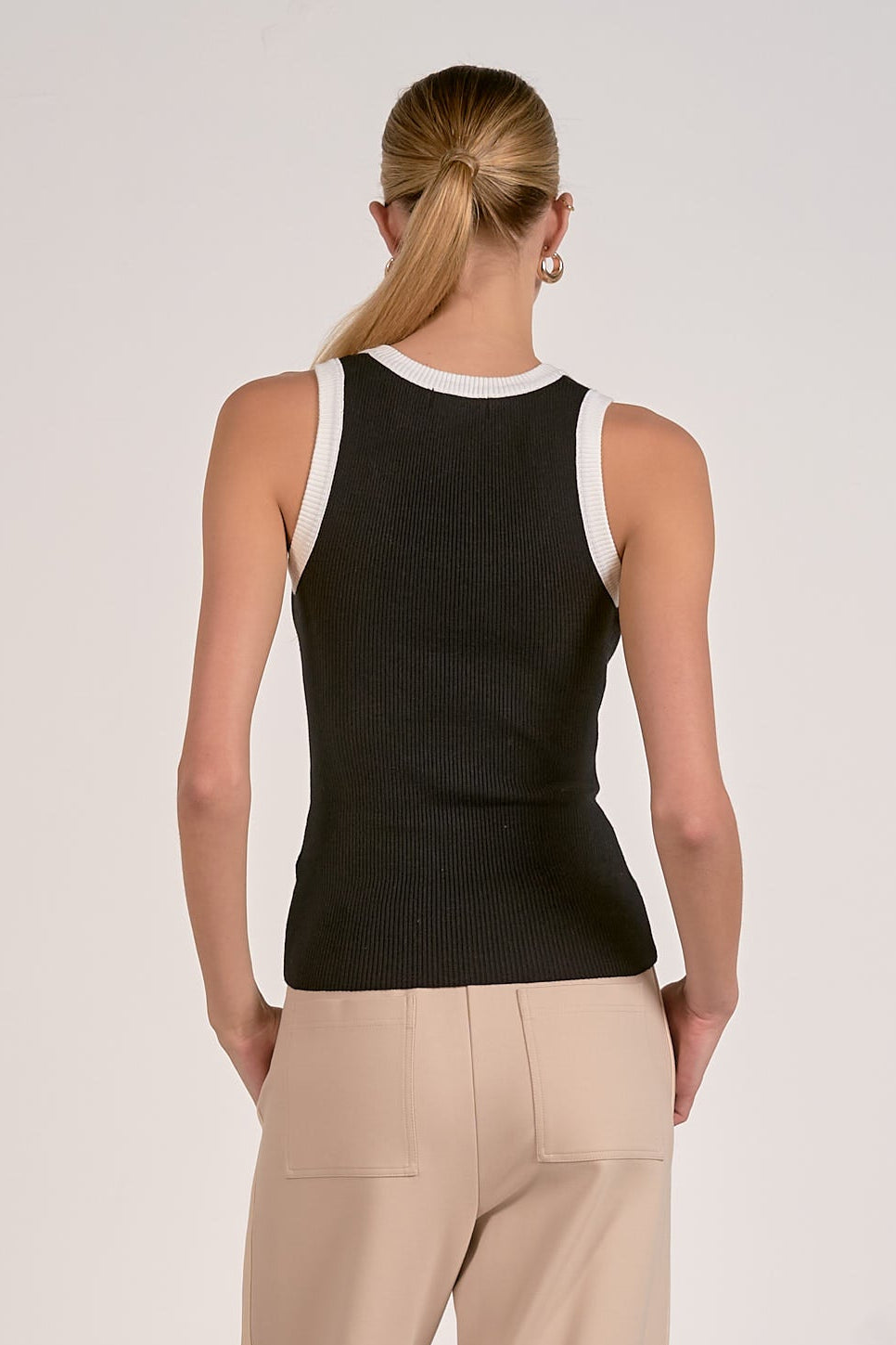 Back view: black knit tank top with white crew-neck trim, sleeveless.