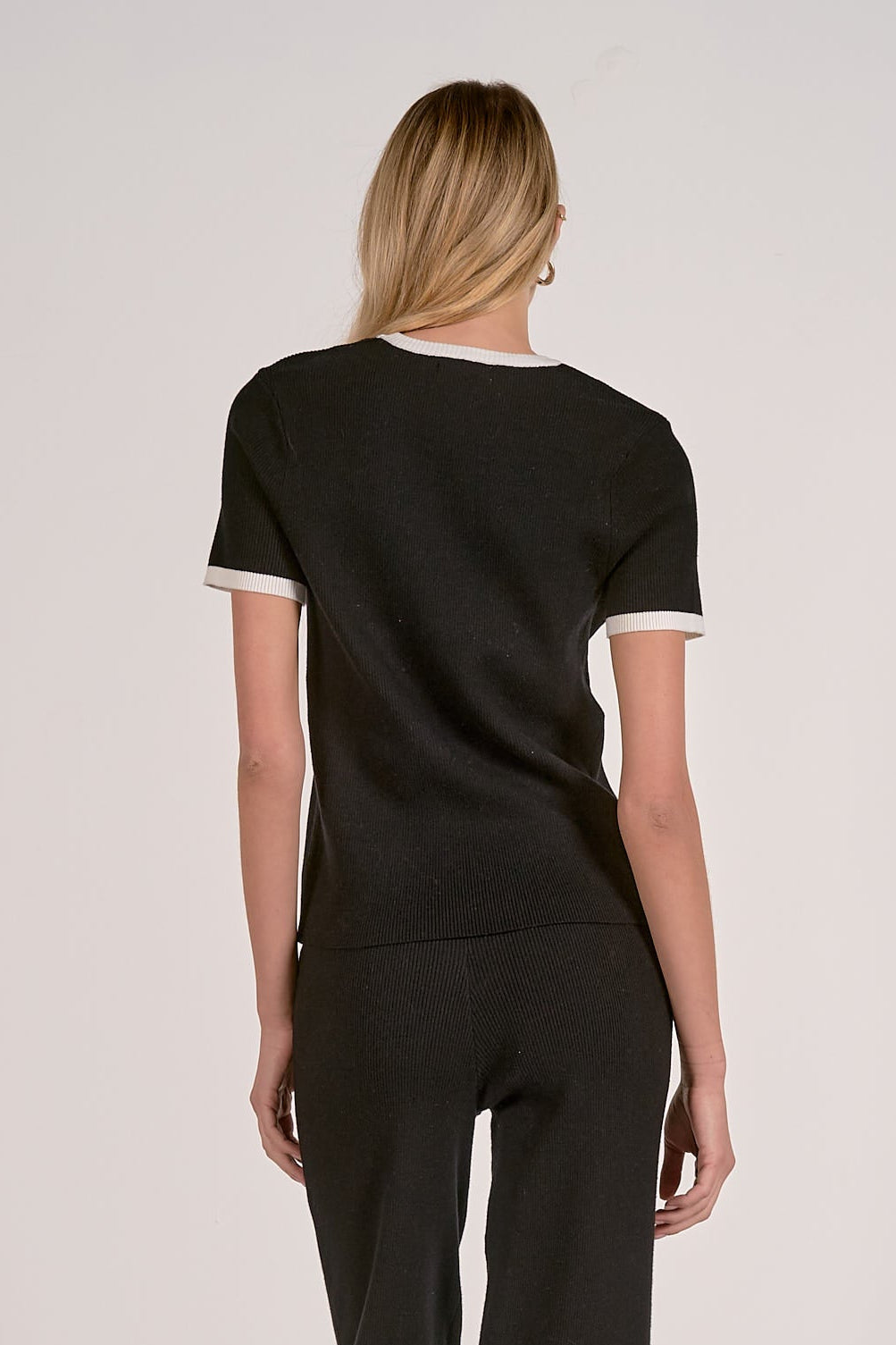 Black crewneck top back view with white ribbed collar and sleeve cuffs