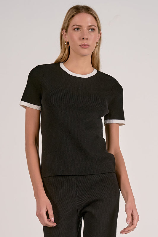 Black crewneck top with white ribbed collar and sleeve cuffs