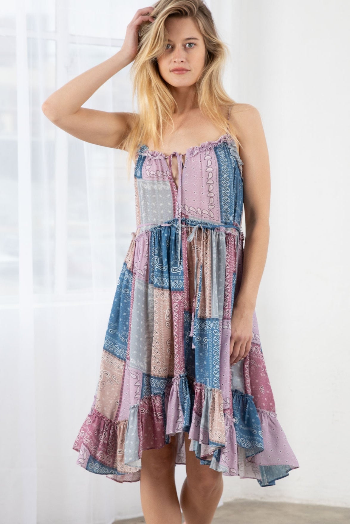Woman wearing a colorful lavender/blue patchwork dress against a white background