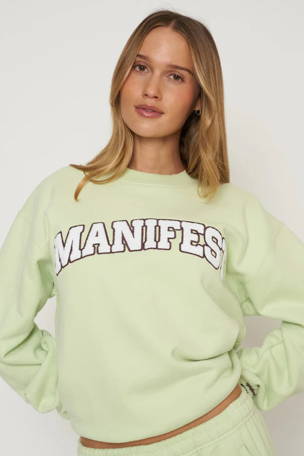 Sage crewneck sweatshirt with long sleeves and MANIFEST graphic across chest