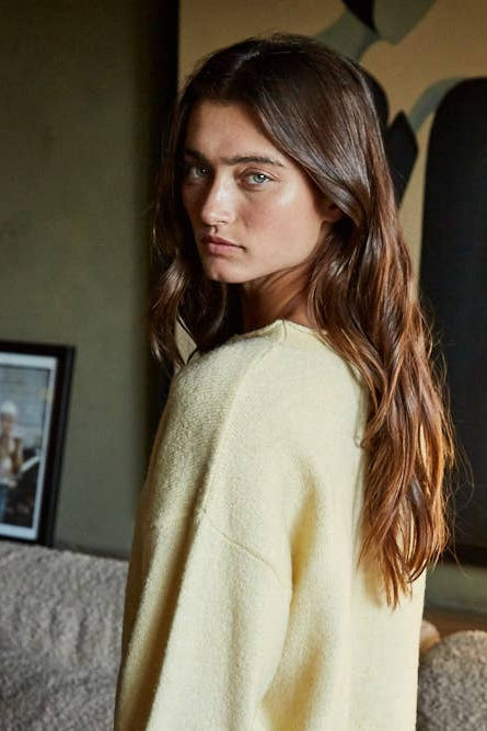 Butter-yellow knit cardigan top in side view with button-front and long sleeves